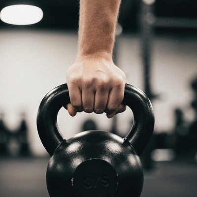 Close-up of a kettlebell with a person's hand gripping it, suggesting proper form